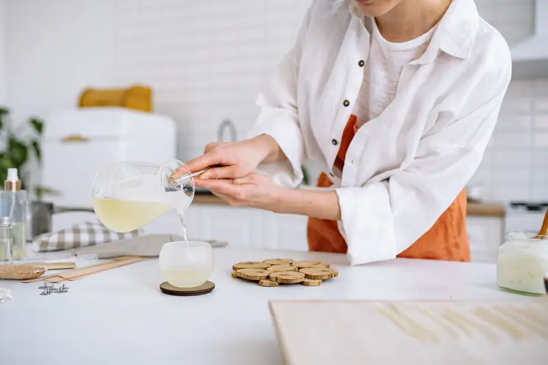 A craftswoman pouring wax into a candle mold in a cozy kitchen. Perfect for DIY and crafting themes