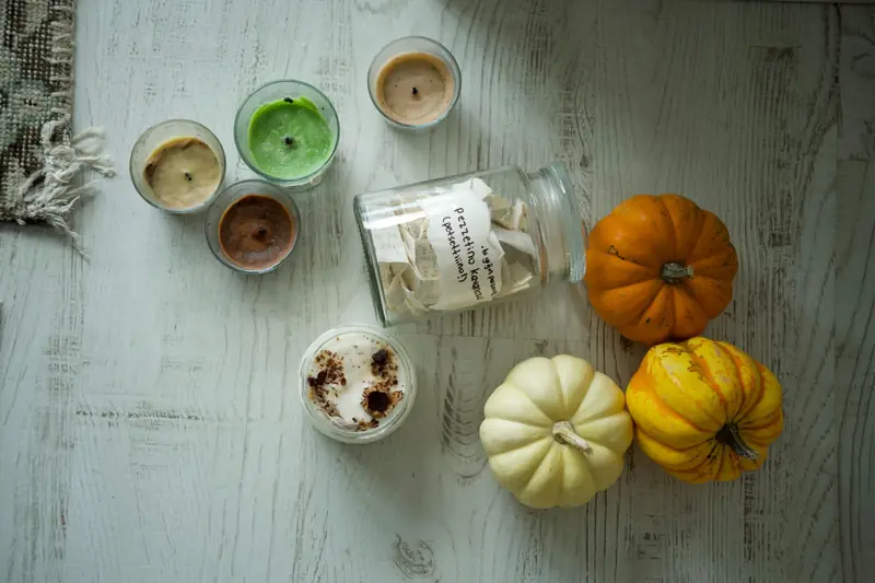 Flat lay of cozy autumn decor with colorful pumpkins and scented candles on a rustic wooden table