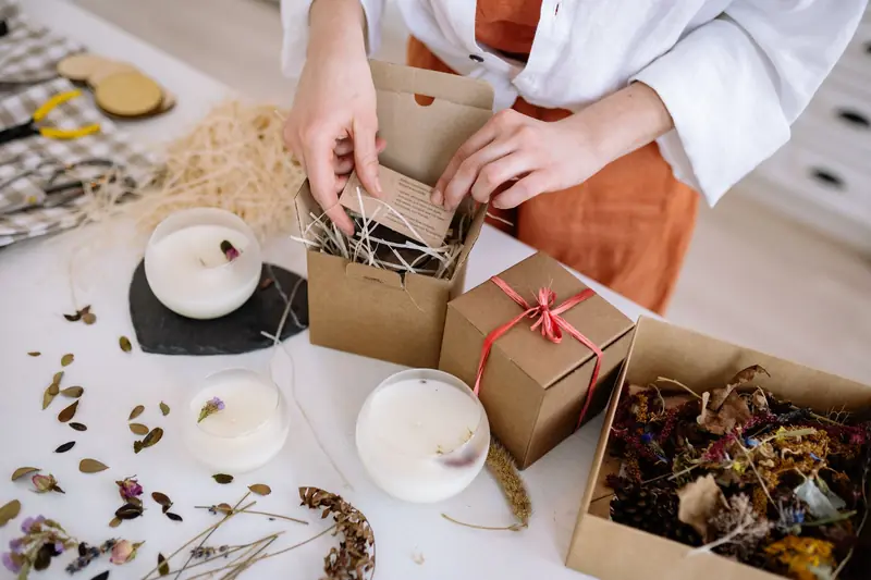 Person assembling eco-friendly candle gift boxes with natural materials