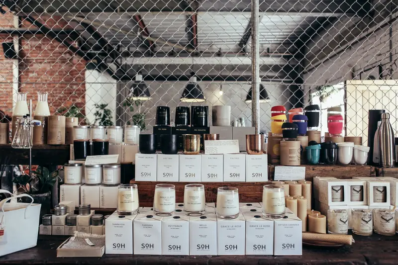 A curated display of handmade candles and home goods on a rustic counter, perfect for cozy interiors